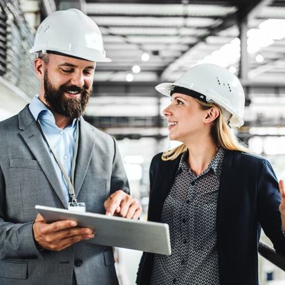 A man and a woman with white helmets talking to each other with a laptop