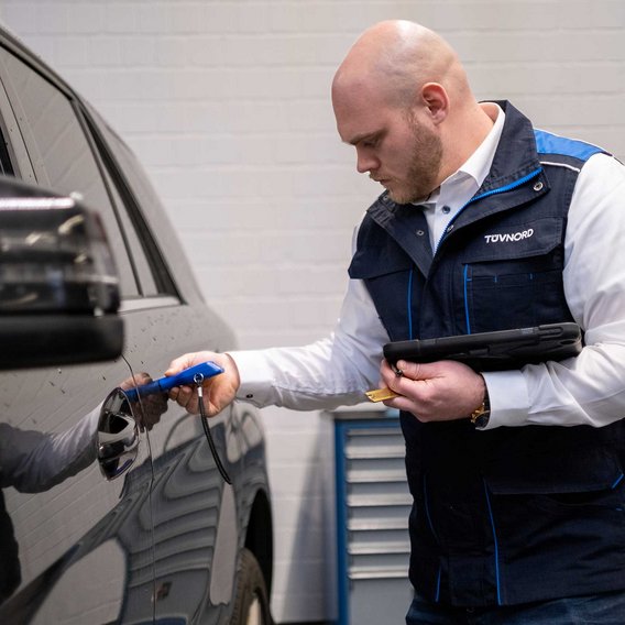 Schadengutachten für Autohäuser und Werkstätten: Fahrzeugprüfung TÜV NORD Sachverständiger prüft den Lack eines Fahrzeugs