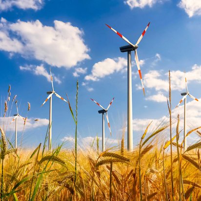 Mehrere Windkraftanlagen auf einem Getreidefeld produzieren Ökostrom.