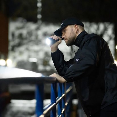 Effektive Sicherheitsschulungen: Security, Deeskalation und Arbeitssicherheit Sicherheitsmitarbeiter bei nächtlicher Patrouille mit Taschenlampe