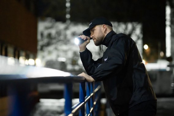 Sicherheitsmitarbeiter bei nächtlicher Patrouille mit Taschenlampe