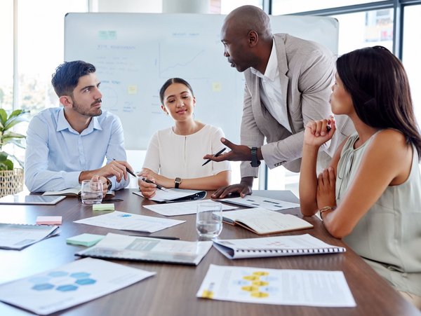 Vier Personen diskutieren gemeinsam in einem modernen Besprechungsraum.