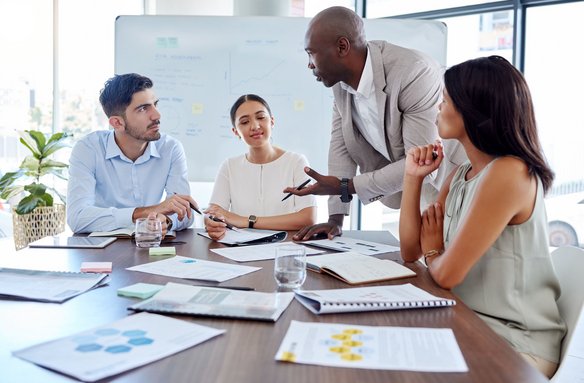 Vier Personen diskutieren gemeinsam in einem modernen Besprechungsraum.