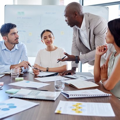 Vier Personen diskutieren gemeinsam in einem modernen Besprechungsraum.
