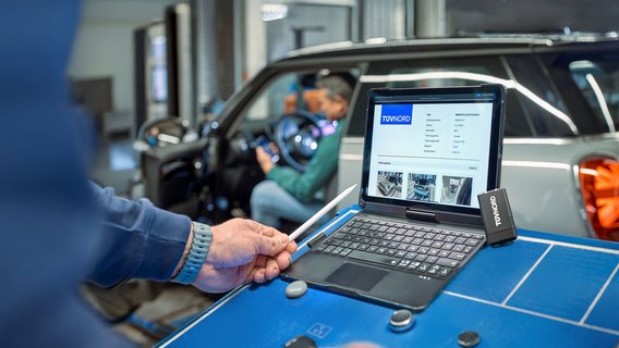 Mitarbeiter bei der Fahrzeugdiagnose mit Laptop an der TÜV NORD Station
