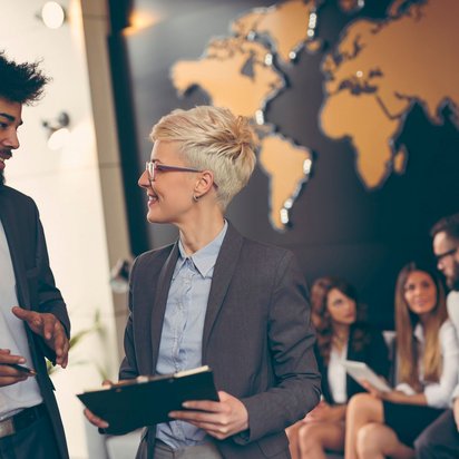 Zwei Geschäftspersonen im Gespräch vor einer Weltkarte