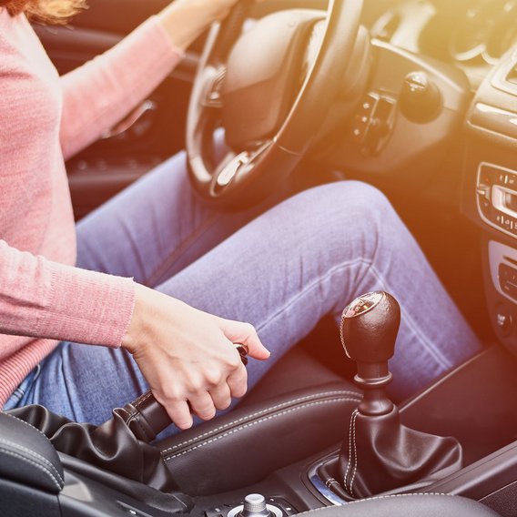 Person betätigt die Handbremse in einem Fahrzeug