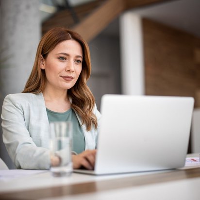 Frau arbeitet an einem Laptop am Schreibtisch