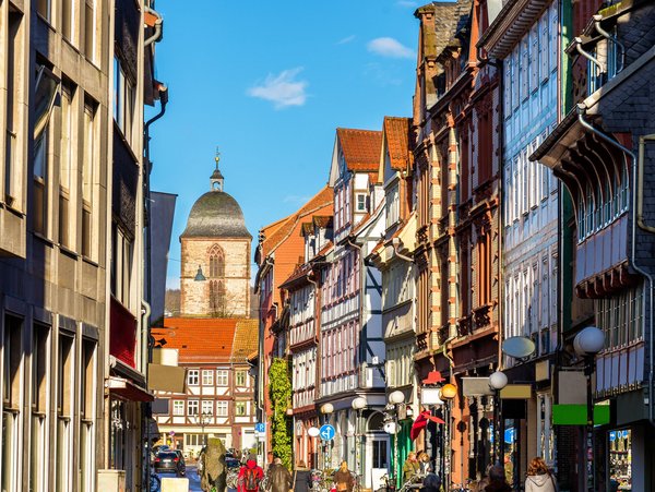 Malerische Altstadtstraße in Göttingen mit Fachwerkhäusern und dem Kirchturm im Hintergrund