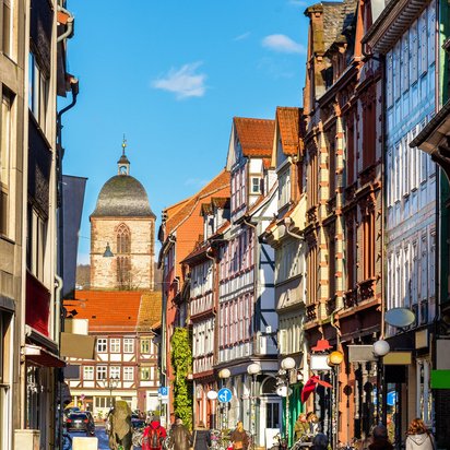 Malerische Altstadtstraße in Göttingen mit Fachwerkhäusern und dem Kirchturm im Hintergrund