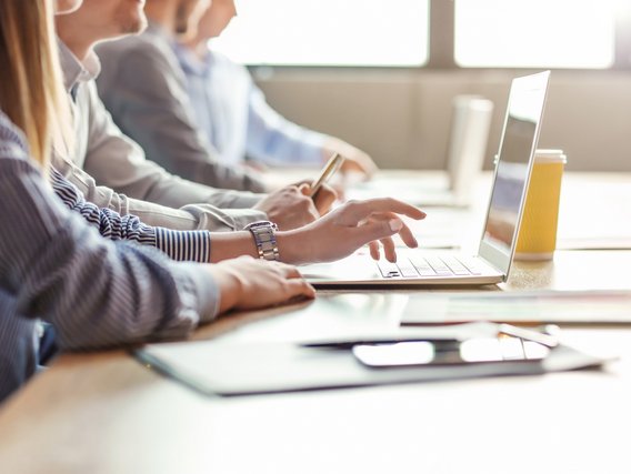Personen arbeiten an Laptops und Tablets in einem Seminarraum – Fokus auf Schulungssituation im Strahlenschutz