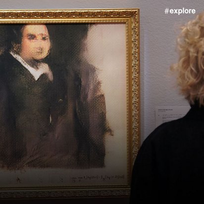 Eine Frau mit blonden lockigen Haaren betrachtet das gerahmte Porträt in einer Galerie, während im Hintergrund weitere Kunstwerke an der Wand zu sehen sind.