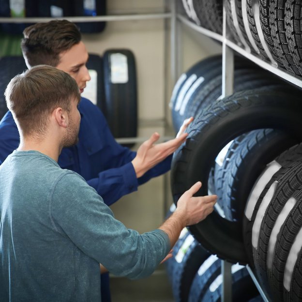 Zwei Personen diskutieren über die Auswahl von Autoreifen in einer Werkstatt
