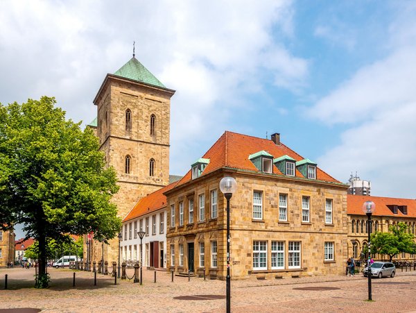 Historisches Gebäude in Osnabrück mit einem Turm und grünem Baum