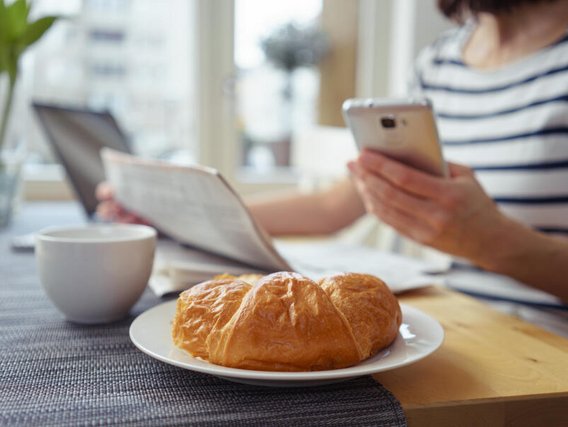Datenschutz und Informationssicherheit für Hotels und Gastronomie Digitale Gästekommunikation im Hotel: Gast nutzt Smartphone beim Frühstück. Datenschutz, DSGVO und Informationssicherheit für Hotels und Gastronomiebetriebe.