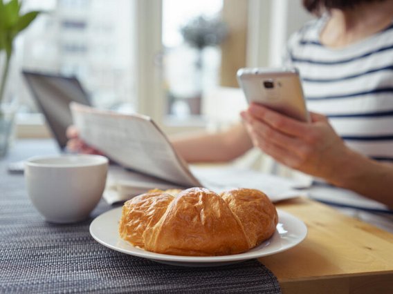 Datenschutz und Informationssicherheit für Hotels und Gastronomie Digitale Gästekommunikation im Hotel: Gast nutzt Smartphone beim Frühstück. Datenschutz, DSGVO und Informationssicherheit für Hotels und Gastronomiebetriebe.