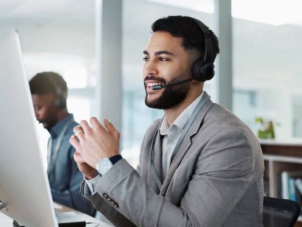 Mitarbeiter im Callcenter, der mit einem Headset arbeitet und ein Gespräch führt