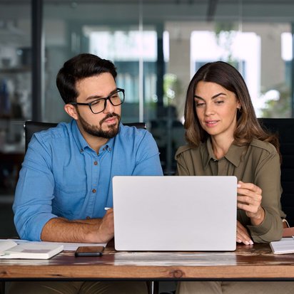 Zwei Personen sitzen am Laptop, um gemeinsam Potenziale für eine Stellensuche durch den TÜV NORD Transfer zu ermitteln.