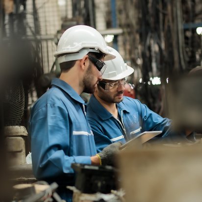 Zwei Personen prüfen die Maschinensicherheit einer Maschine.