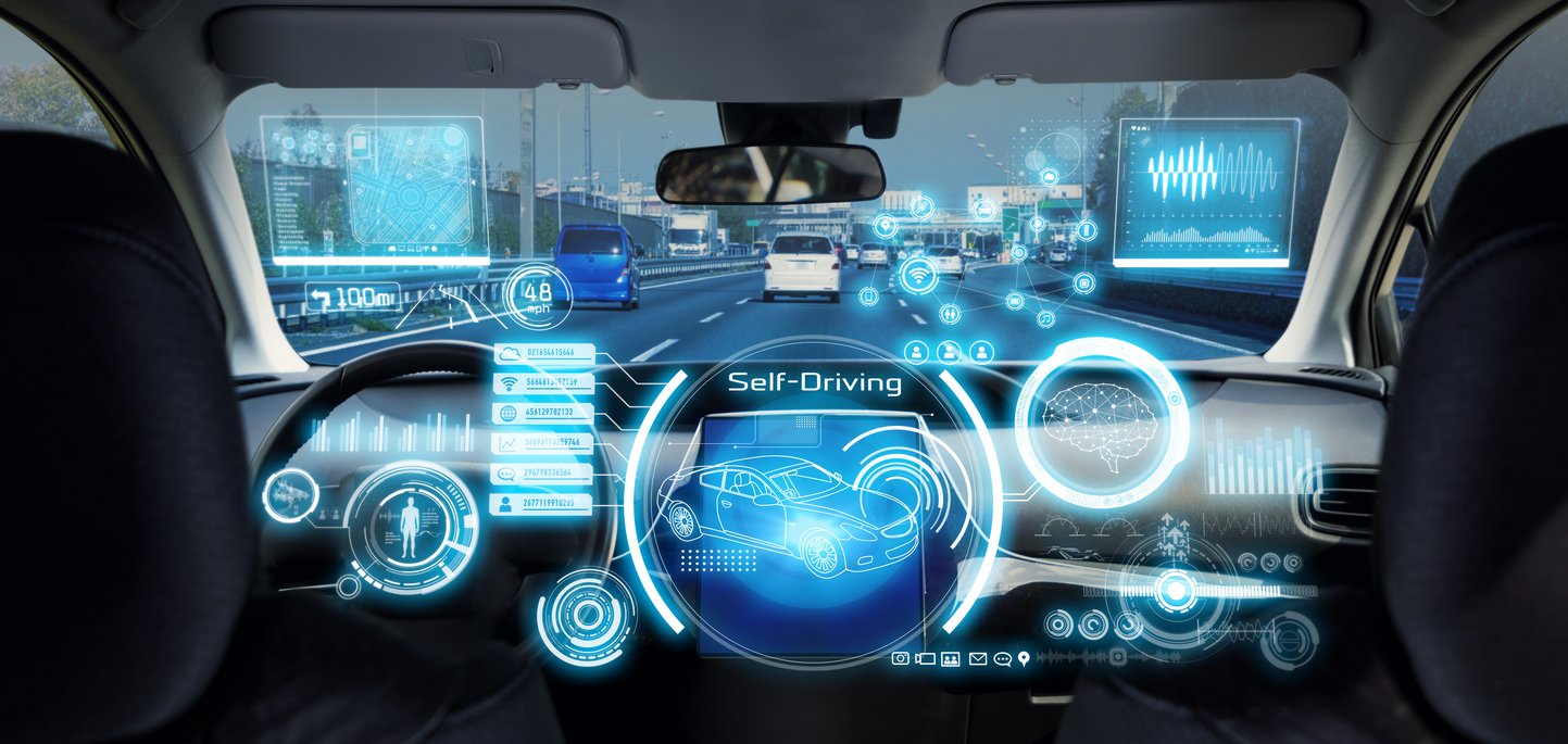 Ein futuristisches Auto-Cockpit mit holographischen Displays und Augmented-Reality-Elementen zeigt "Self-Driving" Technologie. Blaue digitale Interfaces überlagern die Sicht auf eine mehrspurige Autobahn mit anderen Fahrzeugen.
