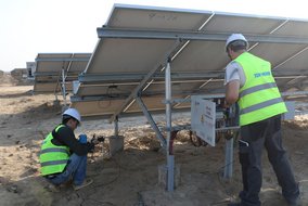 Zwei Techniker der TÜV NORD prüfen die Anschlüsse an einer Solaranlage.