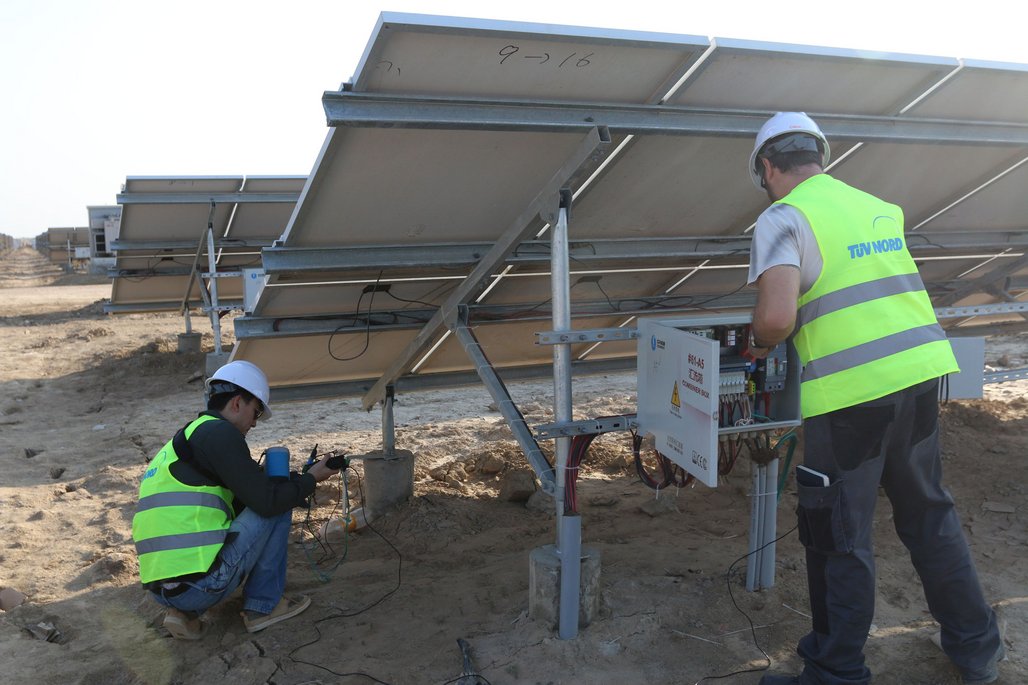 Zwei Techniker der TÜV NORD prüfen die Anschlüsse an einer Solaranlage.