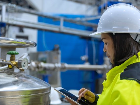 An engineer is working in the production hall and inspecting a valve regulator