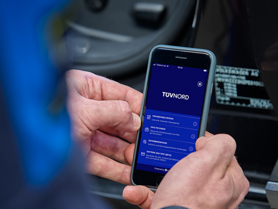 Person hält ein Smartphone mit geöffneter TÜV NORD App zur Fahrzeugdiagnose in der Hand.