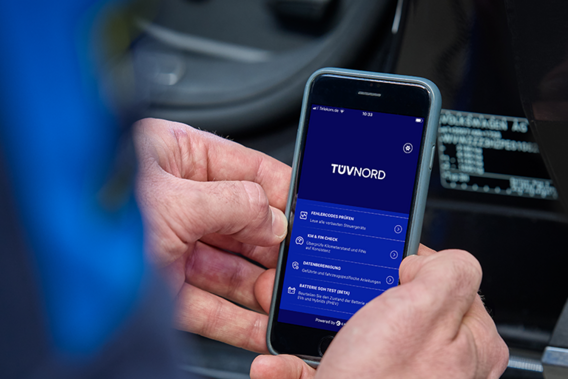 Person hält ein Smartphone mit geöffneter TÜV NORD App zur Fahrzeugdiagnose in der Hand.