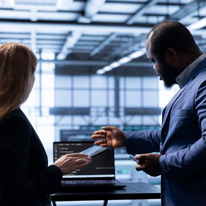 Zwei Geschäftsleute diskutieren vor einem Laptop mit Datenschutz-Warnsymbol auf dem Bildschirm.