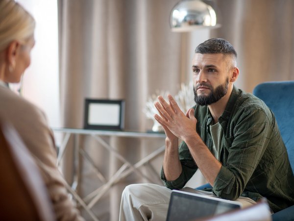 Mann in einem Gespräch, gestikuliert mit den Händen, während er eine andere Person ansieht