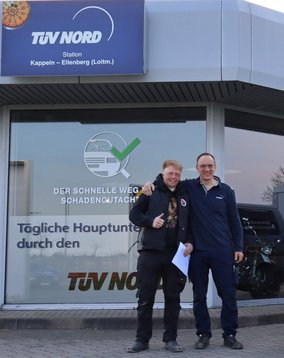 Der Leiter der TÜV NORD Station mit einem zufriedene Kunden vor der TÜV NORD Station Kappeln-Ellenberg