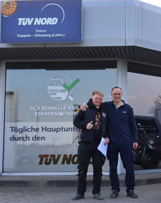 Der Leiter der TÜV NORD Station mit einem zufriedene Kunden vor der TÜV NORD Station Kappeln-Ellenberg