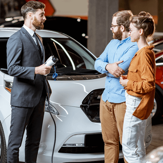 Zwei Männer und eine Frau stehen vor einem weißen Auto