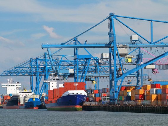 Hafen, Schifffahrt und maritime Infrastruktur – TÜV NORD Dienstleistungen Containerterminal mit Containerschiffen, Hafenkränen und gestapelten Frachtcontainern im Seehafen