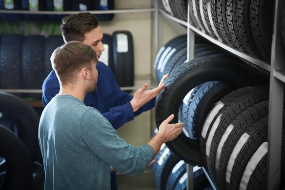 Zwei Personen diskutieren über die Auswahl von Autoreifen in einer Werkstatt