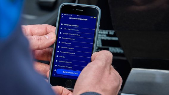 Prüfingenieur überprüft Fahrzeugfehlcodes mit Smartphone
