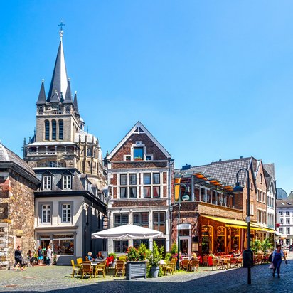Blick auf historische Gebäude und Straßencafés in der Altstadt von Aachen bei Sonnenschein