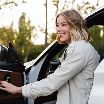 Frau steigt aus Auto bei Sonnenuntergang