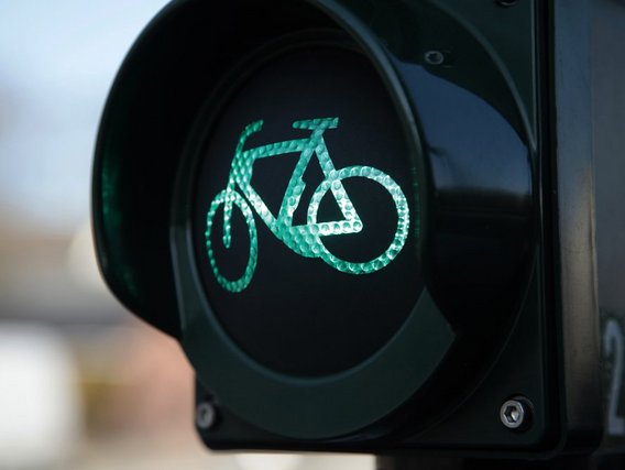 Nahaufnahme einer grünen Fahrradampel mit leuchtendem Fahrrad-Symbol aus reflektierenden Punkten auf schwarzem Hintergrund.