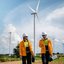 Zwei Techniker vor Windrädern mit Ausrüstung unterwegs