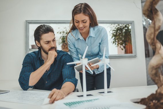 Zwei Personen arbeiten gemeinsam an einem Projekt mit Windradmodellen auf dem Tisch.