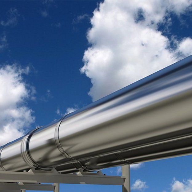 Im Vordergrund zu sehen ist eine silbern glänzende Pipeline, im Hintergrund blauer Himmel mit wenigen weißen Wolken.