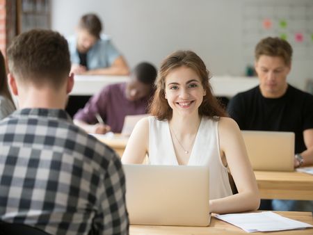 Smiling woman looking at camera sitting at desk in co-working