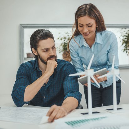 Zwei Personen arbeiten gemeinsam an einem Projekt mit Windradmodellen auf dem Tisch.