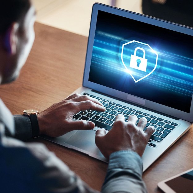 Person arbeitet an einem Laptop mit angezeigtem Datenschutzsymbol auf dem Bildschirm.