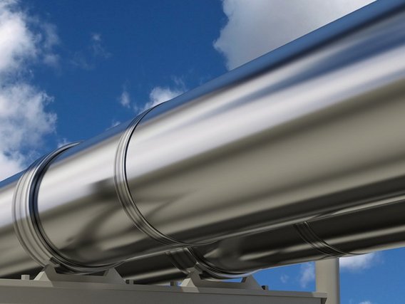 Silbrig glänzende Pipeline vor blauem Himmel mit wenigen Wolken