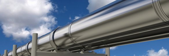 Silbrig glänzende Pipeline vor blauem Himmel mit wenigen Wolken
