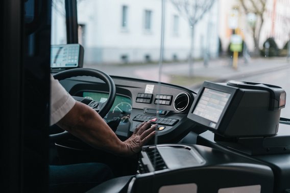 Busfahrer bedient Armaturenbrett und Fahrkartenautomat in einem modernen Linienbus