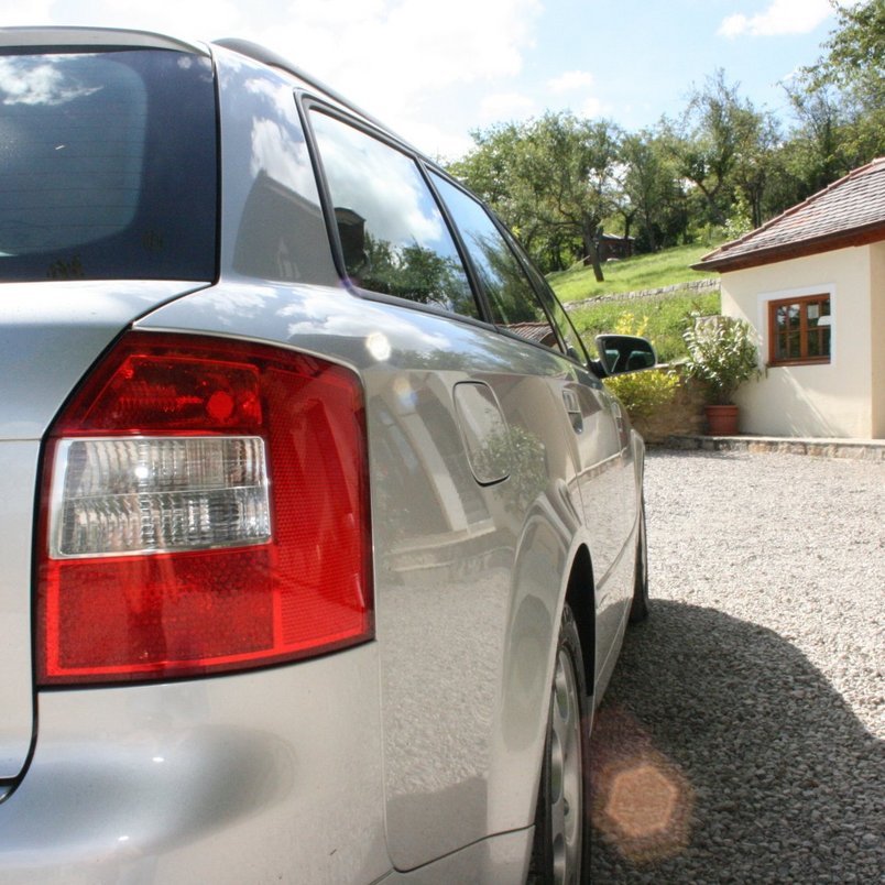 Silbernes Auto auf einem Kiesweg vor einem Landhaus